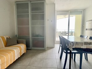 Une pièce comprenant un canapé, une table à manger avec des chaises et une porte-fenêtre coulissante donnant sur un espace extérieur.
