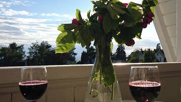 A table with two wine glasses, a vase with flowers, and a bowl of olives.