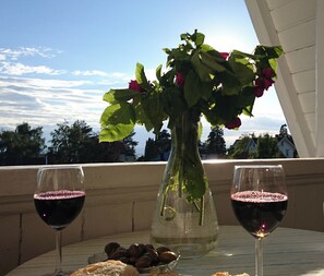 A table with two wine glasses, a vase with flowers, and a bowl of olives. - Villa Sommerfryd Seterveien (Oslo)