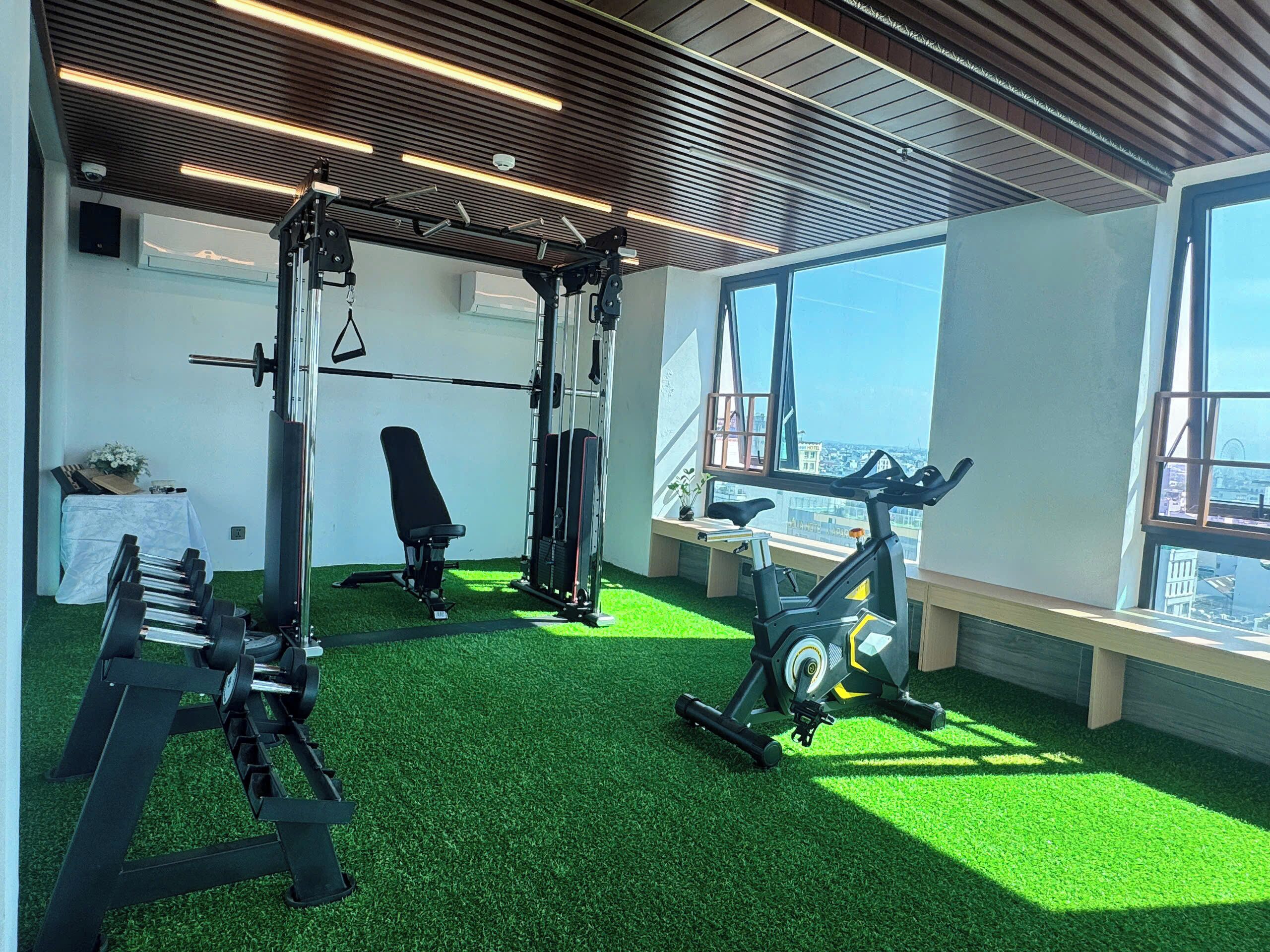 A gym with exercise equipment, a bench, and a view of the city through large windows.