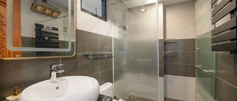 Un baño moderno con un lavamanos blanco, un inodoro y una zona de ducha con mampara de vidrio.
