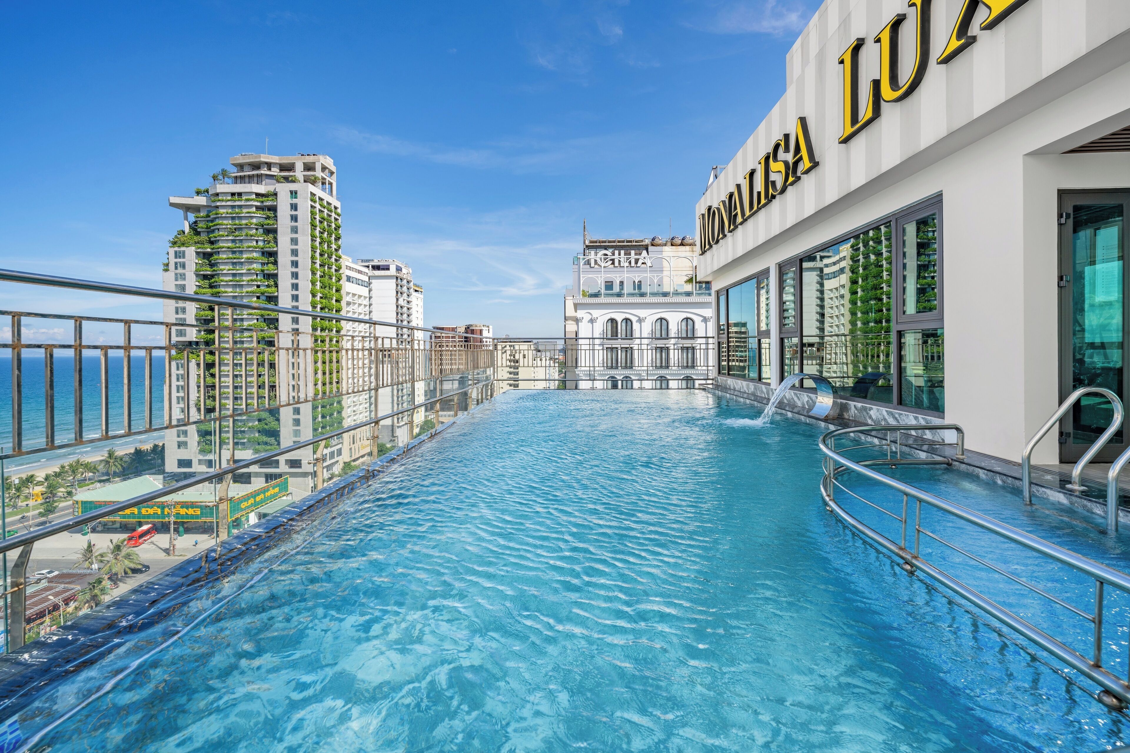 A rooftop infinity pool with a view of the city skyline, including a hotel named "MONALISA LUX".