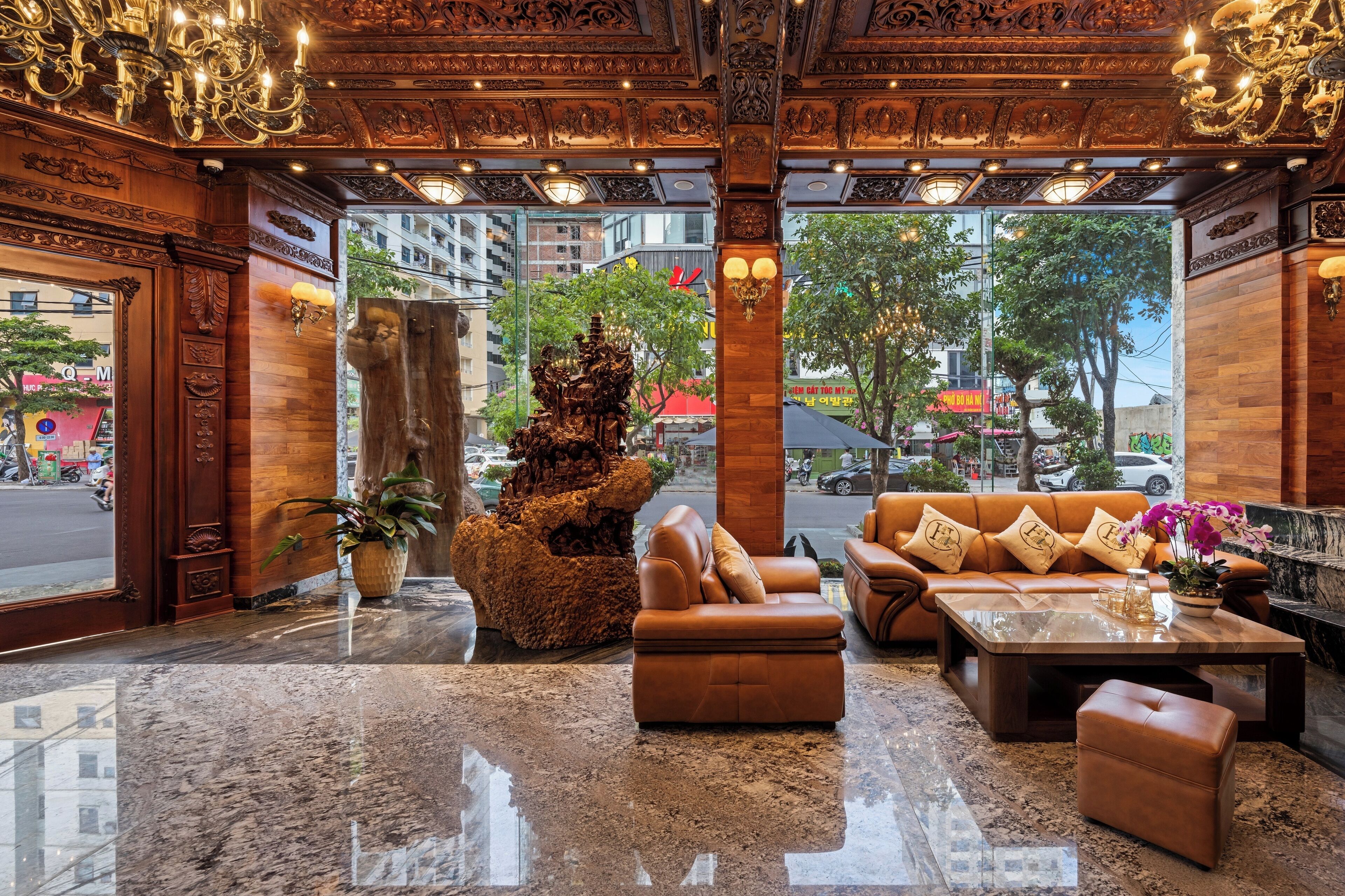 A lobby with a wooden ceiling, a large rock sculpture, leather sofas, and a marble floor.