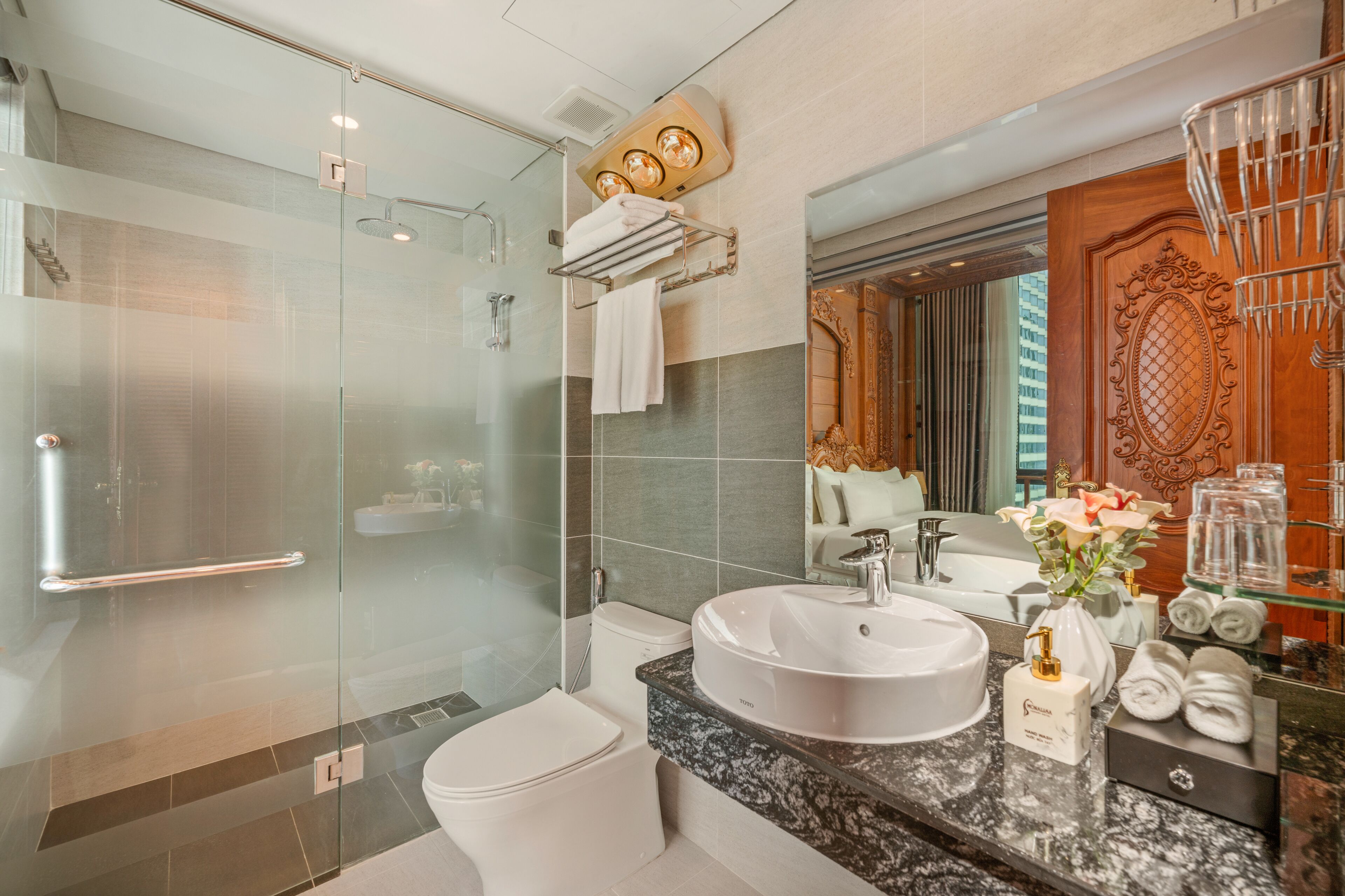 A modern bathroom with a glass-enclosed shower, a white sink, and a vanity with a marble countertop.