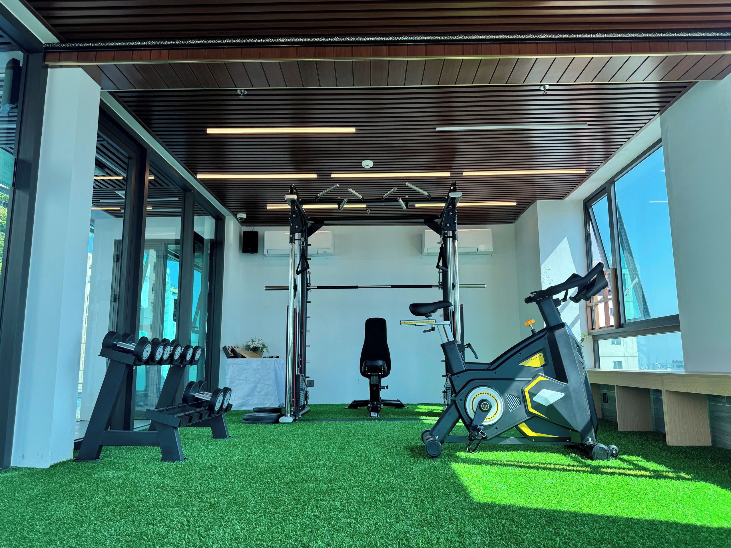 A gym with a pull-up bar, dumbbells, an exercise bike, and a bench.