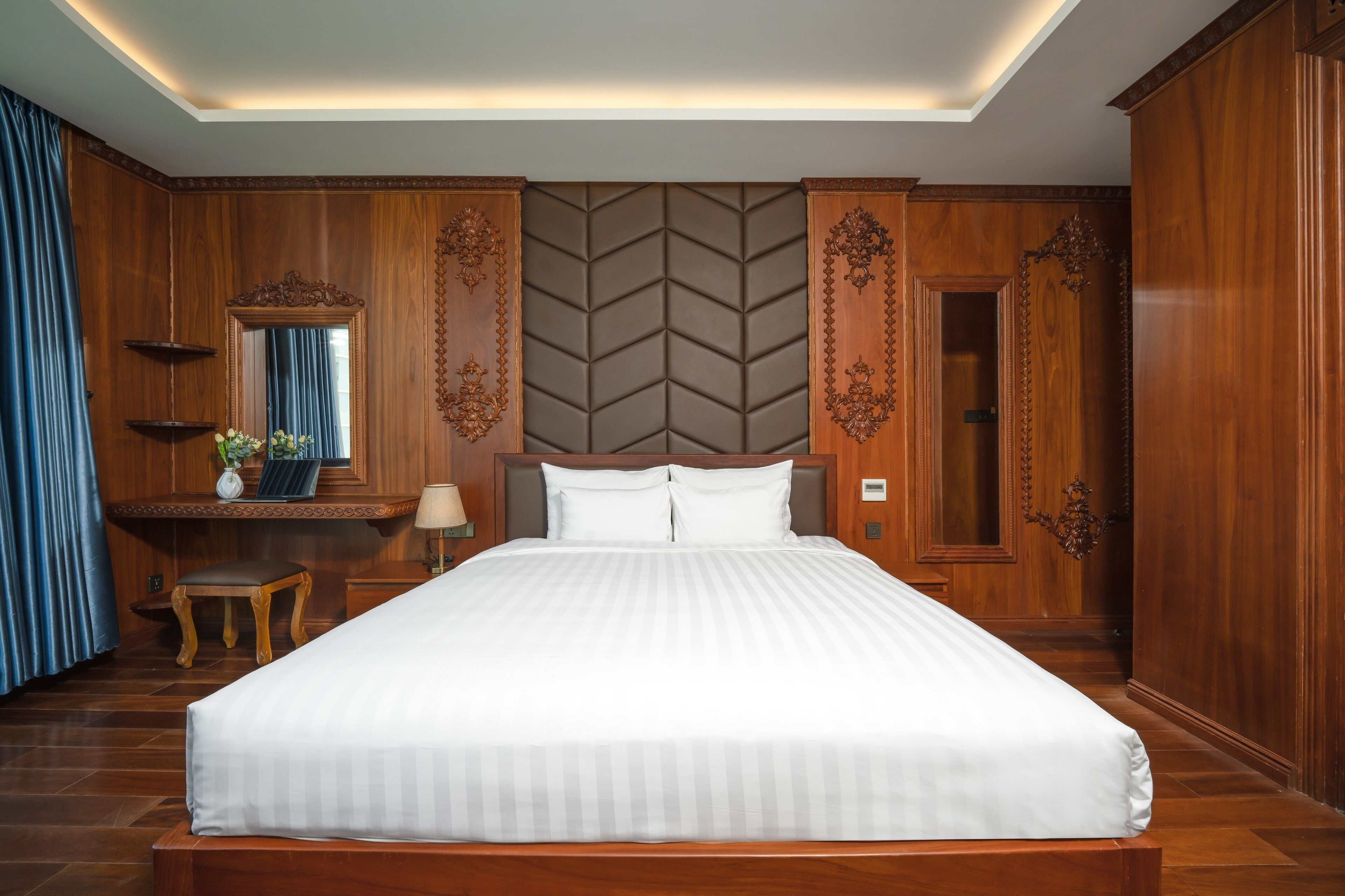 A large bed with a wooden headboard, a bedside table with a lamp, and a mirror.