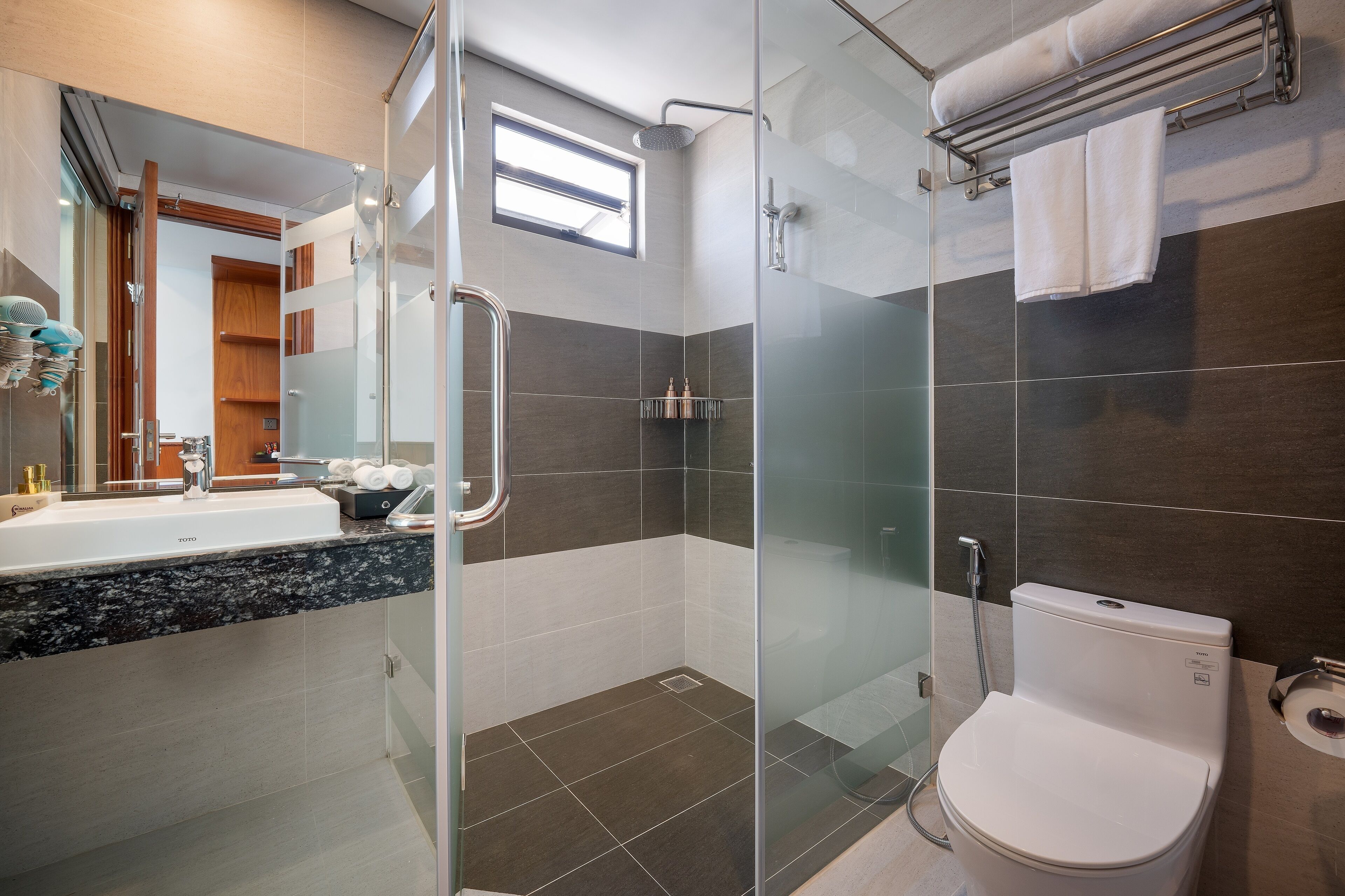 A modern bathroom with a glass-enclosed shower, a white toilet, and a vanity with a sink.