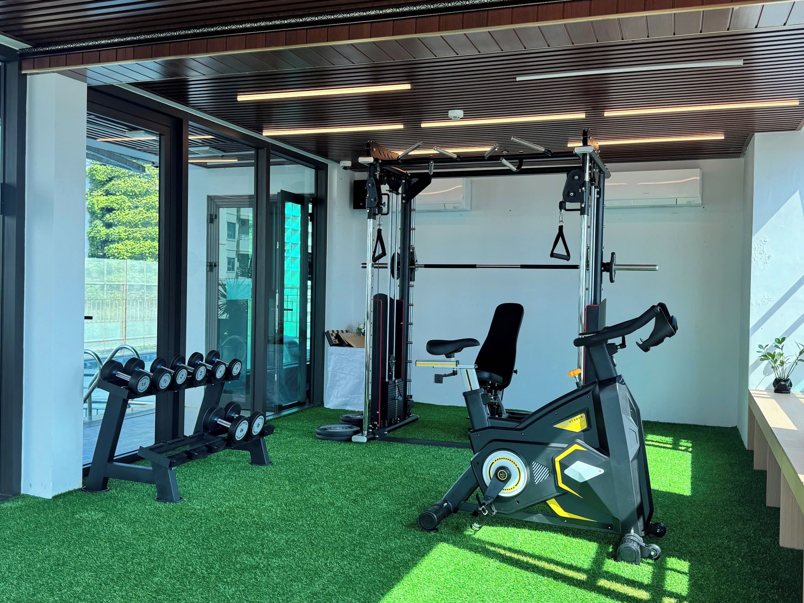 A gym with exercise equipment, a bench, and a wall-mounted TV.