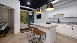 A modern kitchen with white cabinets, a granite countertop, and a bar area with stools.