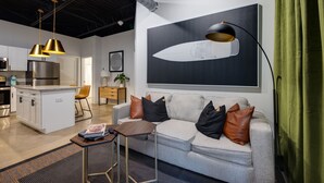 A modern living room with a grey sofa, a coffee table, and a large artwork of a rocket on the wall.