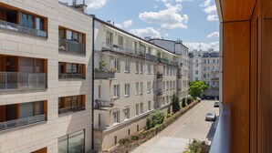 A modern apartment building with multiple balconies, a clear street view, and a well-maintained garden area.