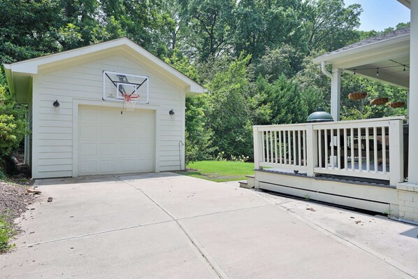 A white garage with a basketball hoop, a covered porch, and a well-maintained lawn.