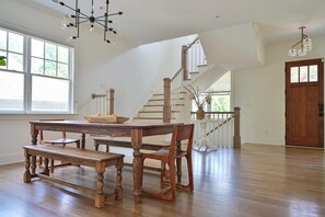 Un vaste espace dédié à la salle à manger, avec une table et des bancs en bois, un escalier et une vue sur l’extérieur.