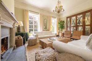 A cozy living room with a fireplace, white sofas, a wooden coffee table, and a large window with curtains. - The Vicarage - Great Limber, Lincolnshire (Great Limber)