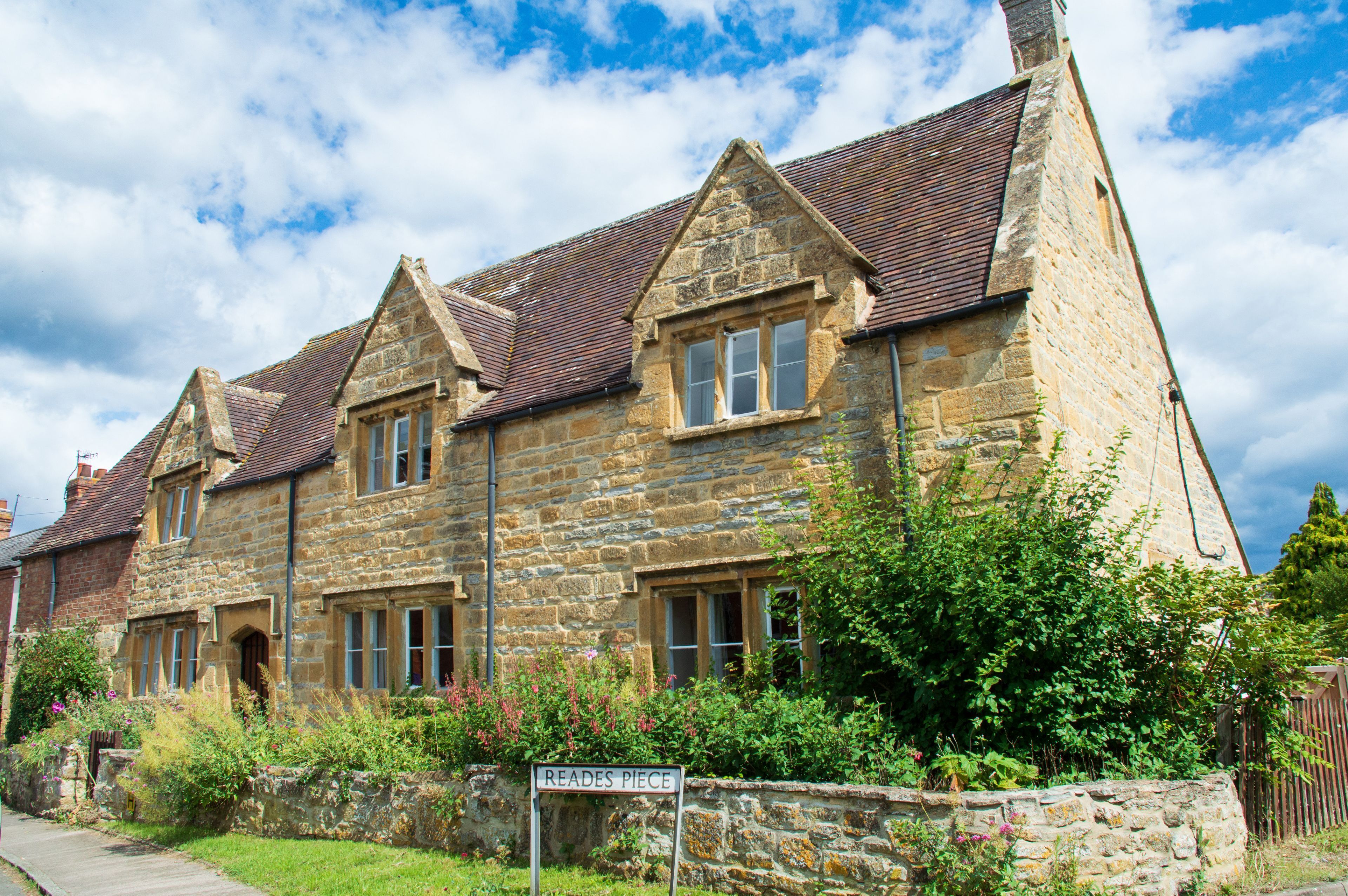 A stone building with a traditional pitched roof and multiple windows.