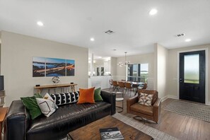 A modern living room with a leather sofa, dining area, and a view of the outdoors.