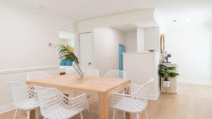 A dining area with a wooden table and white wireframe chairs, a blue refrigerator, and a potted plant. - Beachside 2BR Retreat in Cocoa Beach (Cocoa Beach)