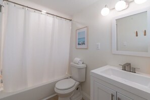 Ein Badezimmer mit Duschvorhang, Toilette, Waschbecken und Spiegel.