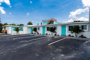 A motel with a parking lot, a staircase, and a small building with a turquoise door. - THE JUNI ✺ Stunning Studio, Walk to Everything (Cocoa Beach)