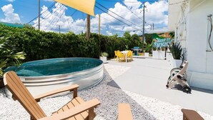 A backyard with a swimming pool, outdoor seating, and a covered area.
