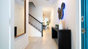 Ein moderner Flur mit Treppe, einem schwarzen Konsolentisch und dekorativen Accessoires sowie einer blauen Tür.