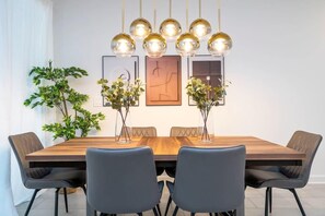Enjoy dining in this stylish space with a large table and comfortable seating for six, surrounded by modern lighting and a beautiful piece of artwork.