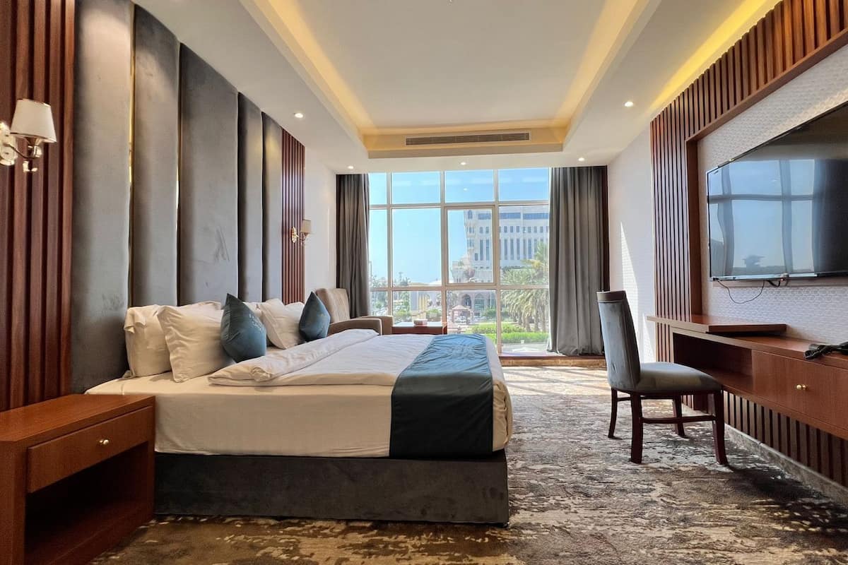 Une chambre d’hôtel avec un grand lit, un bureau, une chaise, une télévision et une vue sur la ville.