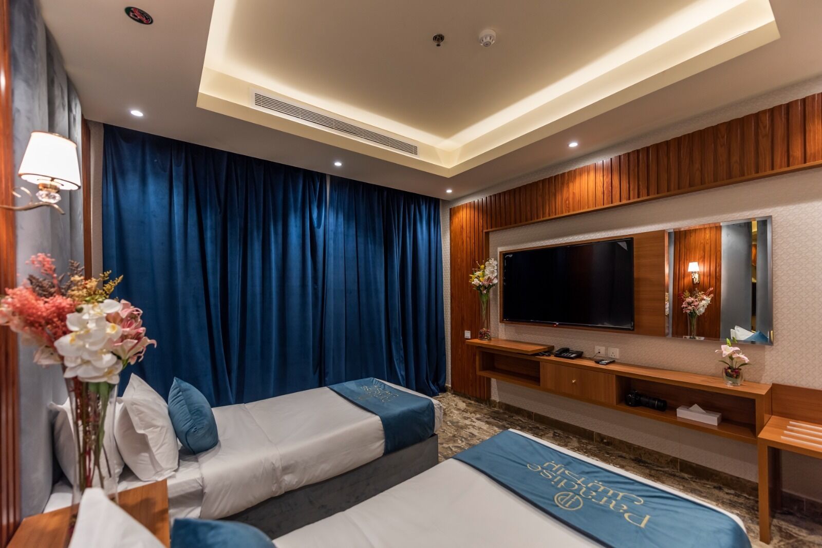 Une chambre d’hôtel avec deux lits, un grand téléviseur à écran plat, une console en bois et un miroir.