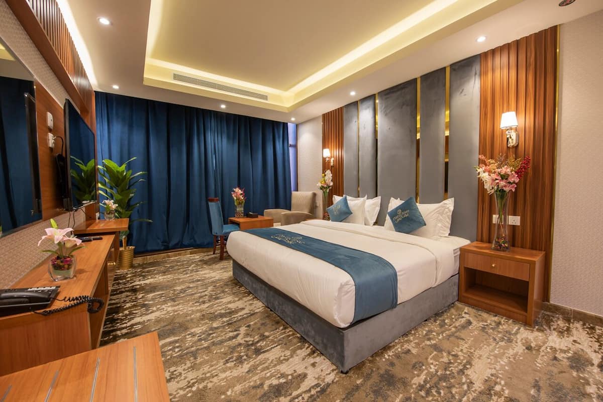 Une chambre d’hôtel moderne équipée d’un grand lit, d’un bureau, d’une chaise et d’un espace de réception.
