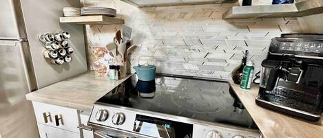 Una cocina compacta con estufa a gas, horno y cafetera.