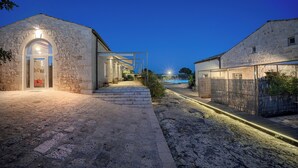 A stone building with a well-lit entrance and steps leading to a covered area.