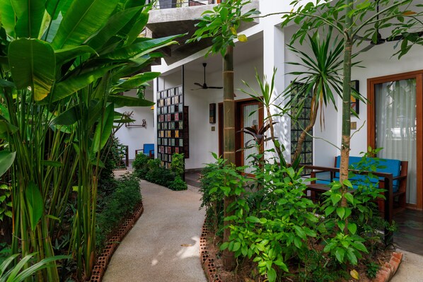 A modern indoor garden with a concrete staircase, a ceiling fan, and a blue sofa. - SAKABAN Suite (Siem Reap)