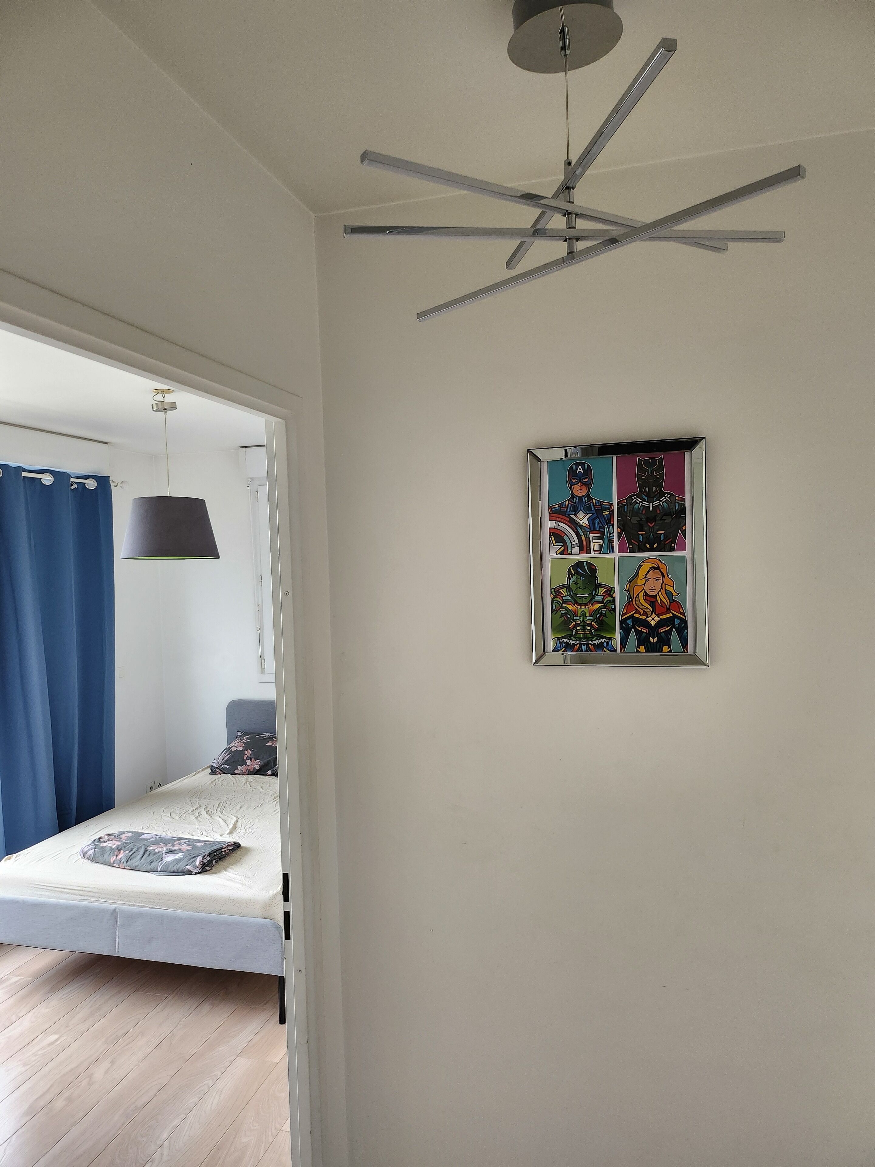 Un dormitorio con cama, ventilador de techo y un cómic enmarcado en la pared.