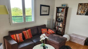 A living room with a brown leather sofa, a round white coffee table, a bookshelf, and a framed picture on the wall.