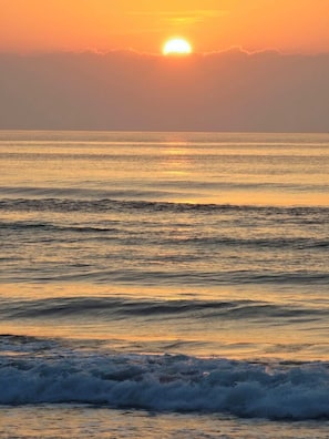 A sunset over the ocean with calm waves. - Hibnb Guesthouse (Zhuangwei)