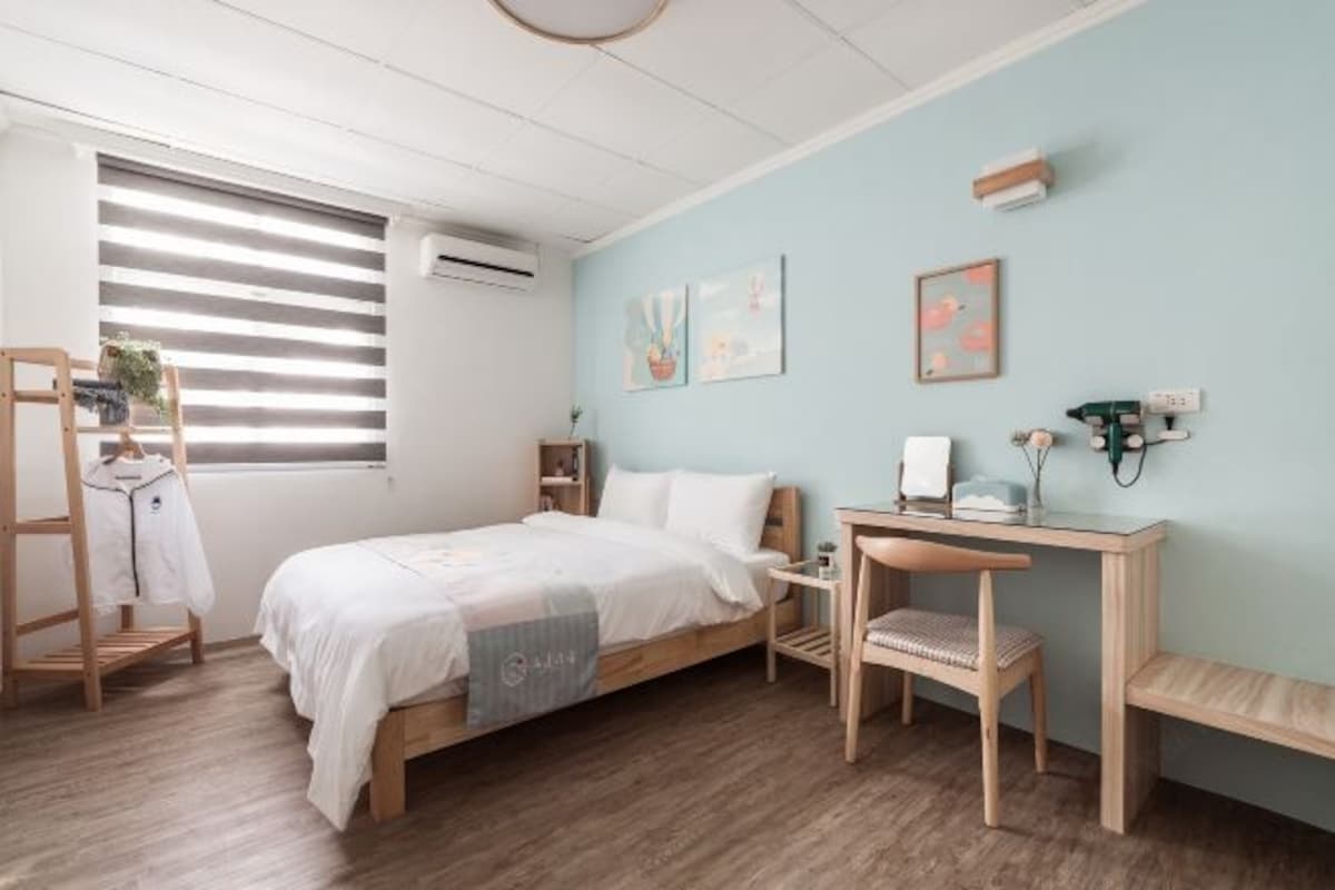 A bedroom with a bed, a desk, a chair, and a wardrobe.