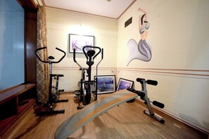 A home gym with exercise equipment, a bench, and a wall with a painting. - Hari Mahal Palace-By Pachar Group (Jaipur)