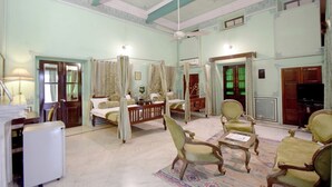 A spacious room with a large bed, a sitting area with chairs, a television, and a refrigerator. - Hari Mahal Palace-By Pachar Group (Jaipur)