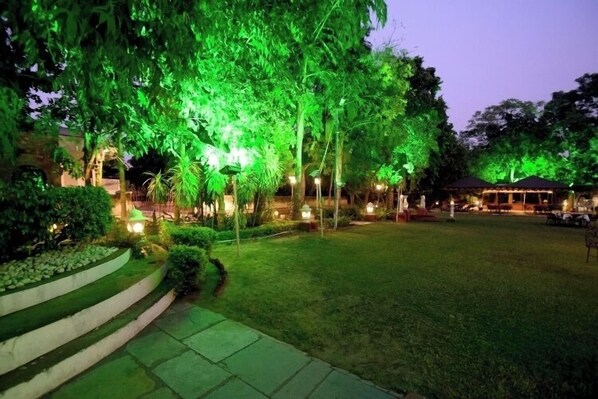 A well-lit outdoor area with a grassy lawn, steps leading up to a building, and a gazebo in the background. - Hari Mahal Palace-By Pachar Group (Jaipur)