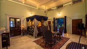 A spacious room with a large bed, a dining table with chairs, a television, and a fireplace. - Hari Mahal Palace-By Pachar Group (Jaipur)