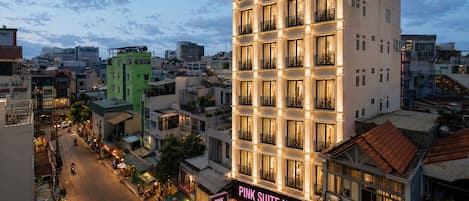 A multi-story hotel with balconies and a sign reading 'Pink Suite Hotel.'