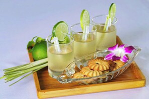 Three glasses of a beverage with lime slices, a dish of cookies, and a flower on a tray. - Pink Suite Saigon Airport Hotel (Ho Chi Minh City)