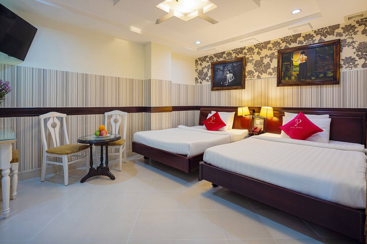Une chambre d’hôtel avec deux lits, une petite table avec des fruits, une chaise et un téléviseur.