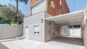 Un'area esterna riparata con pavimento piastrellato, una porta bianca e un condizionatore.