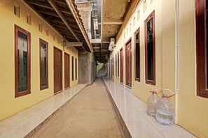 A corridor with doors on both sides, a tiled floor, and two water jugs against the wall. - OYO 91987 Archery Residence Syariah (Sewon)
