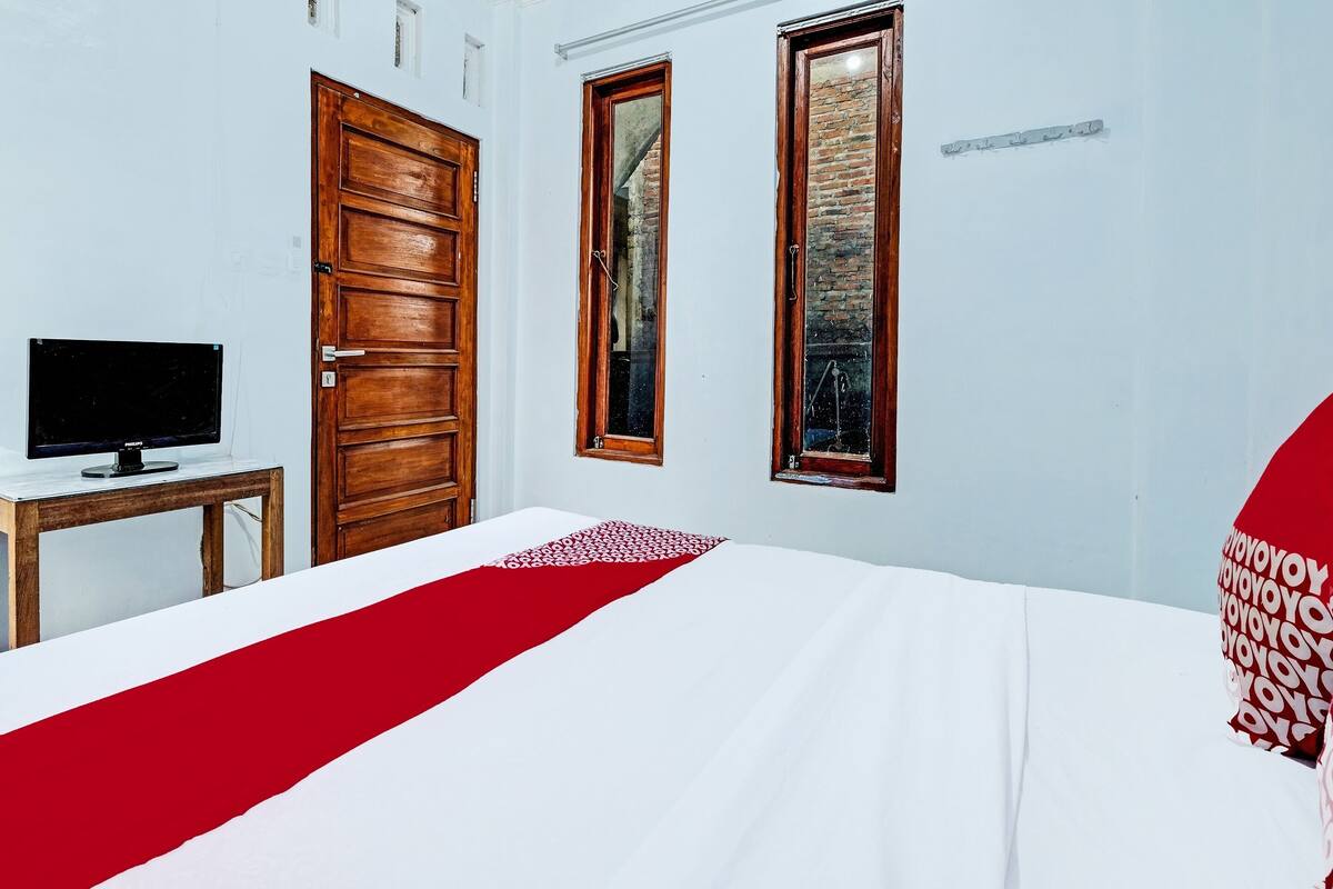 Una habitación de hotel con una cama, un televisor sobre una mesa de madera y dos puertas.