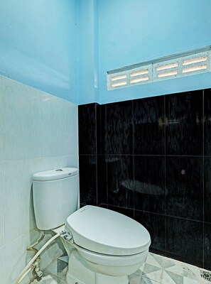 A bathroom with a white toilet, black tiled walls, and a blue ceiling. - OYO 91987 Archery Residence Syariah (Sewon)
