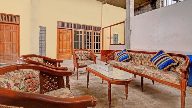 A spacious living area with wooden furniture and a large window. - OYO 91987 Archery Residence Syariah (Sewon)