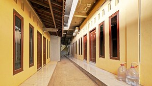 A corridor with yellow walls, wooden doors, and tiled flooring. - OYO 91987 Archery Residence Syariah (Sewon)