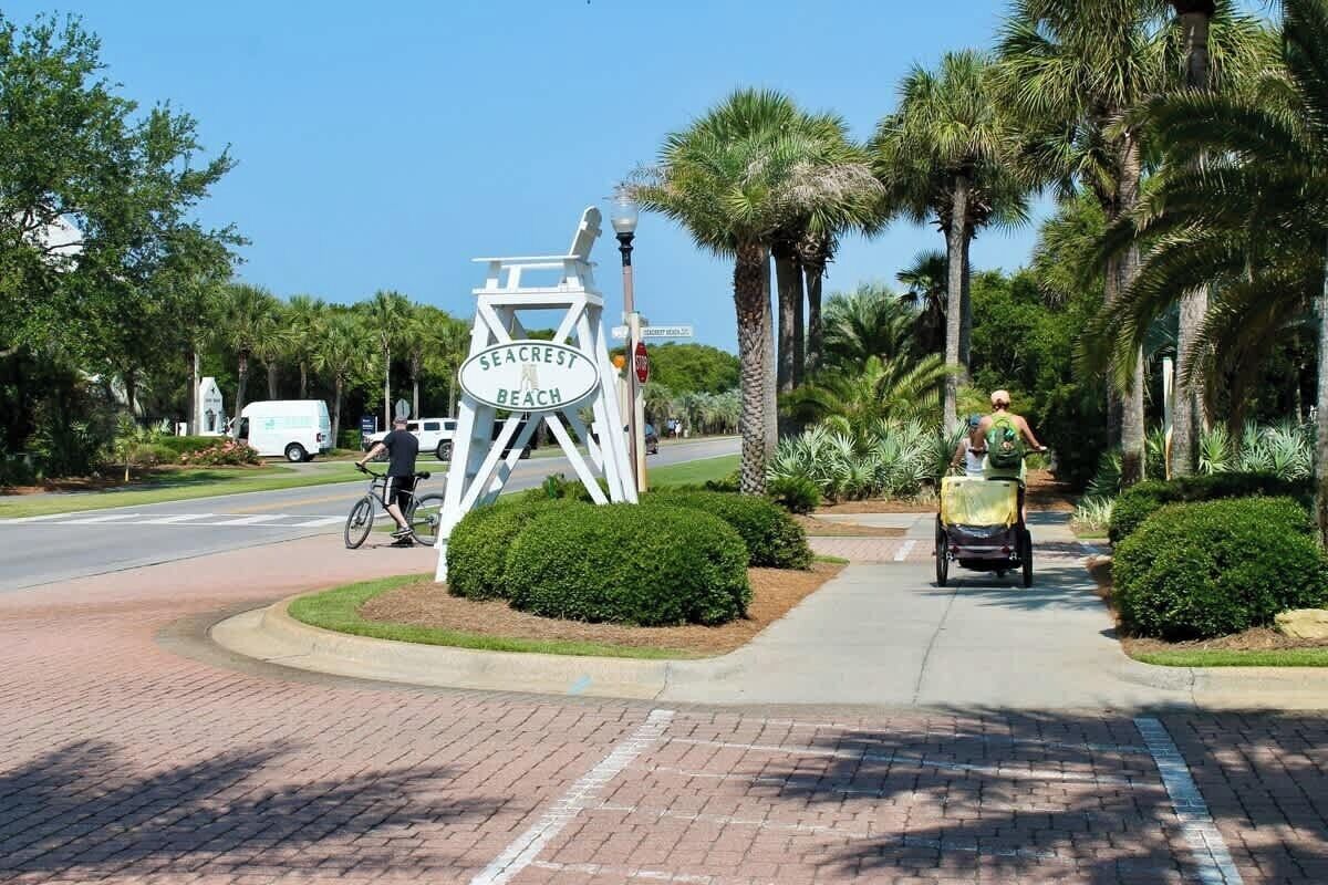 A sign for Seacrest Beach, a paved pathway, and a cyclist.